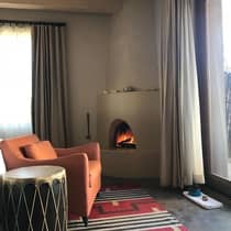 Orange armchair and drum-like side table beside modern clay fireplace