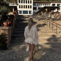 A woman in dressy attire walks towards a stone staircase outside of Four Seasons Resort Mallorca at Formentor