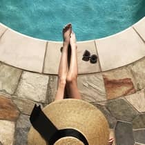 Guest in sunhat relaxing by the pool