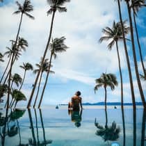 Guest relaxing by the pool surrounded by palm trees