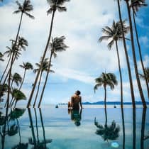 Guest relaxing by the pool surrounded by palm trees