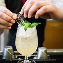 Bartender garnishing a cocktail over ice 
