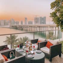 Patio armchairs and small table with dessert platter, cocktails on balcony