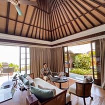 Man wearing robe relaxes in chair with wine glass in open air corner