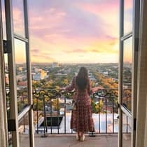 A woman standing on a balcony at sun set.