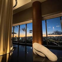 Four Seasons lounge area with large windows overlooking a city skyline at sunset
