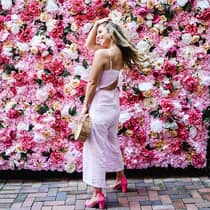 Smiling woman poses in front of wall of roses
