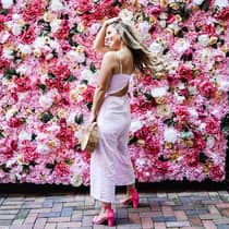 Smiling woman poses in front of wall of roses