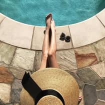 Guest in sunhat relaxing by the pool