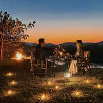 A couple enjoying a candlelit outdoor dinner at sunset