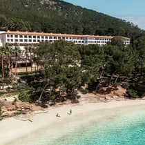 Two guests lounge on a beach in front of Four Seasons Resort Mallorca at Formentor