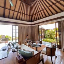 Man wearing robe relaxes in chair with wine glass in open air corner