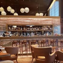 Stools at glass bar, mid-century style lounge chairs