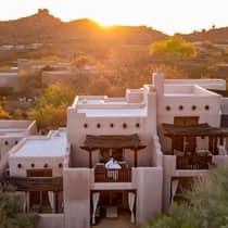 Aerial view of a couple standing on a balcony with a mountain view behind them at sunset