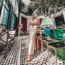 Women stands in lobby by lamp, sofa and potted tree