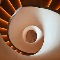 looking down into the center of a spiraling staircase with a smooth white exterior