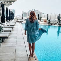 Back of woman walking across outdoor swimming pool deck