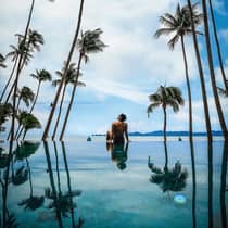 Guest relaxing by the pool surrounded by palm trees