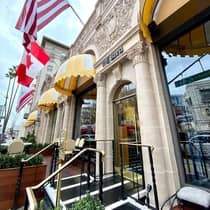 The exterior of a stone building with country flags hanging from it.