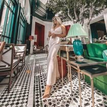 Women stands in lobby by lamp, sofa and potted tree