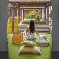 Hotel guest relaxes on a beach hammock under the shade of the palm trees