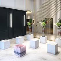 The lobby of the Four Seasons Hotel, Montreal, with large decorative marble blocks, marble flooring, green floral arrangements, and a gold partition