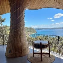 A ceremonial drum beside a wooden circular pillar on a terrace overlooking the water 