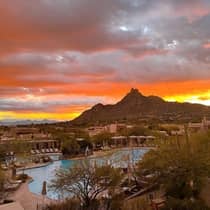 Exterior view of a pool, cabanas and villas at Four Seasons Resort Scottsdale at Troon North, with mountains and sunset behind