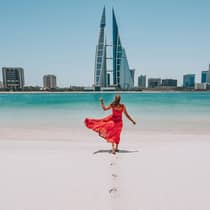 Woman on beach with bahrain city view