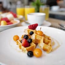 A plate of waffles topped with syrup and fruit