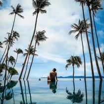 Guest relaxing by the pool surrounded by palm trees