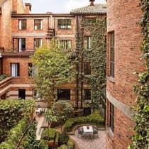 Looking down at courtyard patio surrounded by brick building, windows, green trees, shrubs 