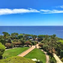 View across green lawn, trees and sea under blue sky
