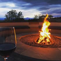 Red wine glass near patio fireplace flame at dusk