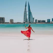 Woman on beach with bahrain city view