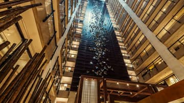 Looking up in 20-storey hotel atrium at 400 stainless-steel butterflies on column