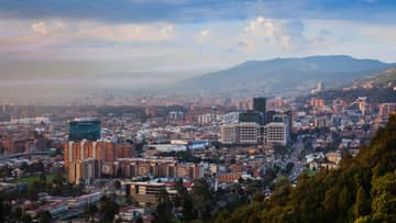 Aerial view of Bogota city, buildings and houses below misty mountains