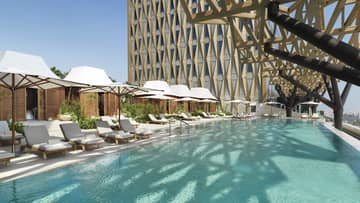 An olympic size pool surrounded by lounge chairs shaded by large white umbrellas