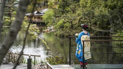A woman in blue kimono gazing over the garden at Four Seasons Hotel Kyoto, a renowned luxury hotel in Kyoto.