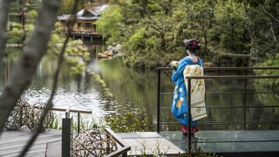 A woman in blue kimono gazing over the garden at Four Seasons Hotel Kyoto, a renowned luxury hotel in Kyoto.