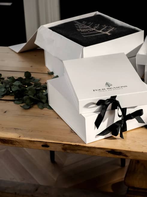 White gift boxes tied with black ribbons sit atop a wooden table