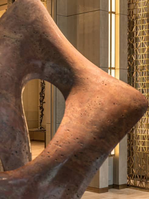 The concierge stands at the front desk with some sculptures beside the entrance