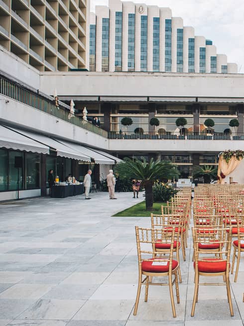 Wedding event set-up with red chairs in rows along outdoor patio and long fountain 