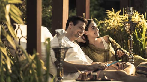 A couple sits together on lounge chairs outside at Four Seasons Hotel Kuala Lumpur