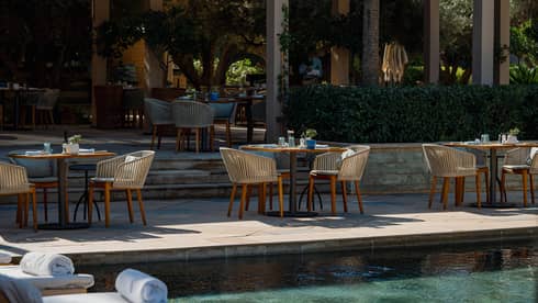 Round tables on tiered poolside deck restaurant
