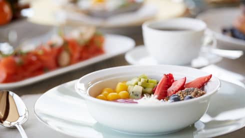 White bowl with fresh fruit, granola on in-room dining tray