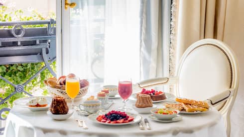 Dining chair with round table set with breakfast foods beside window