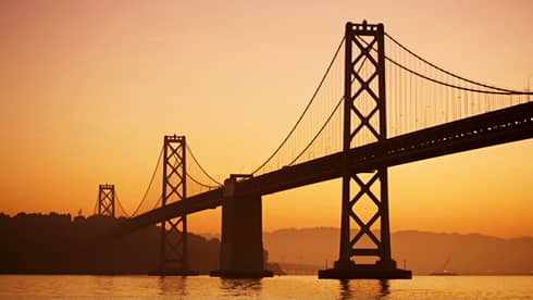 Silhouette of Golden Gate Bridge against an orange sunset 