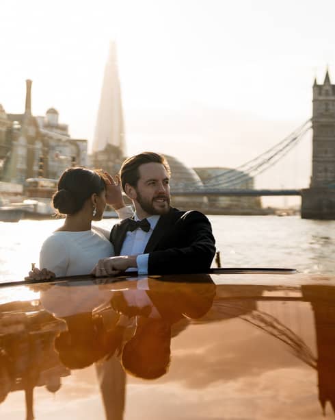 A couple enjoy on a romantic river cruise, surrounded by iconic city landmarks.
