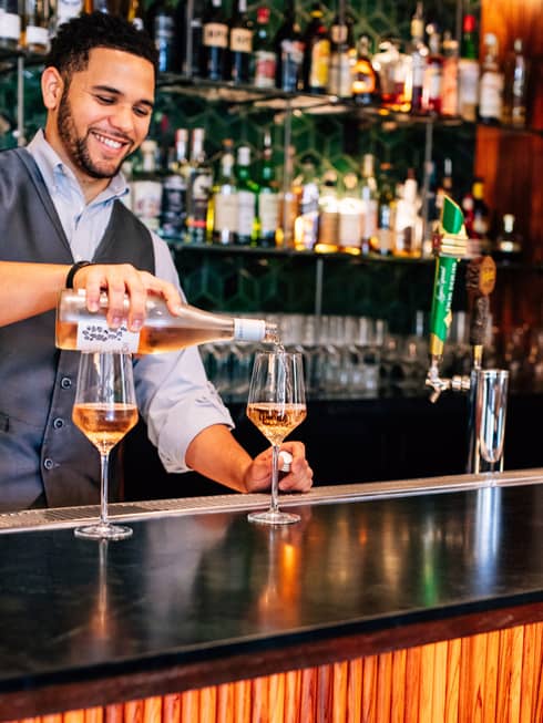A bartender pouring a glass of wine.